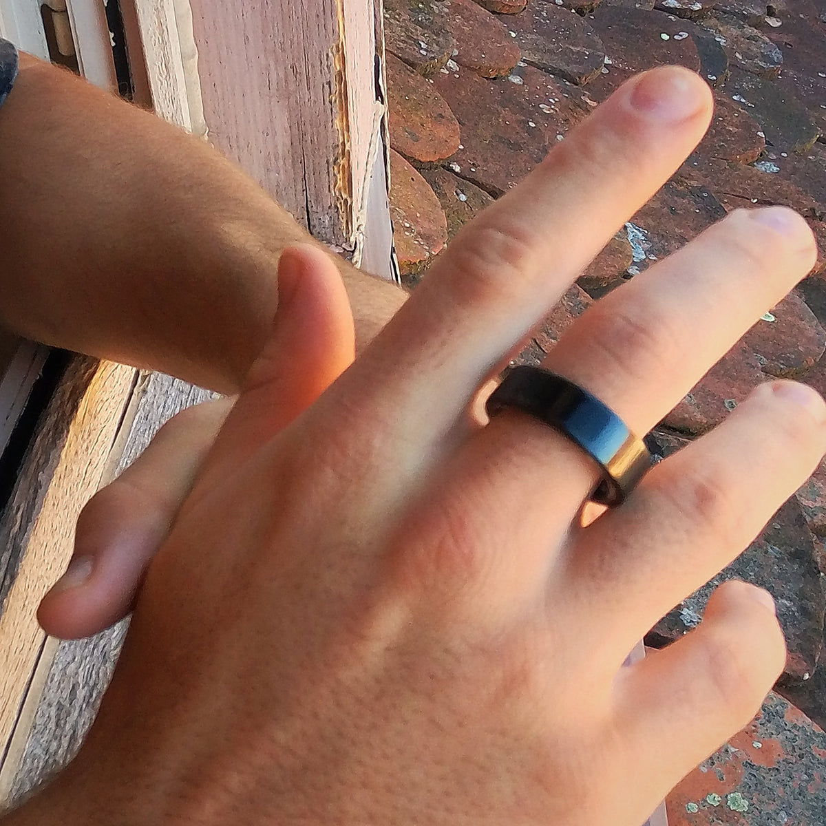 Main ouverte portant la bague connectée noire, en lumière naturelle