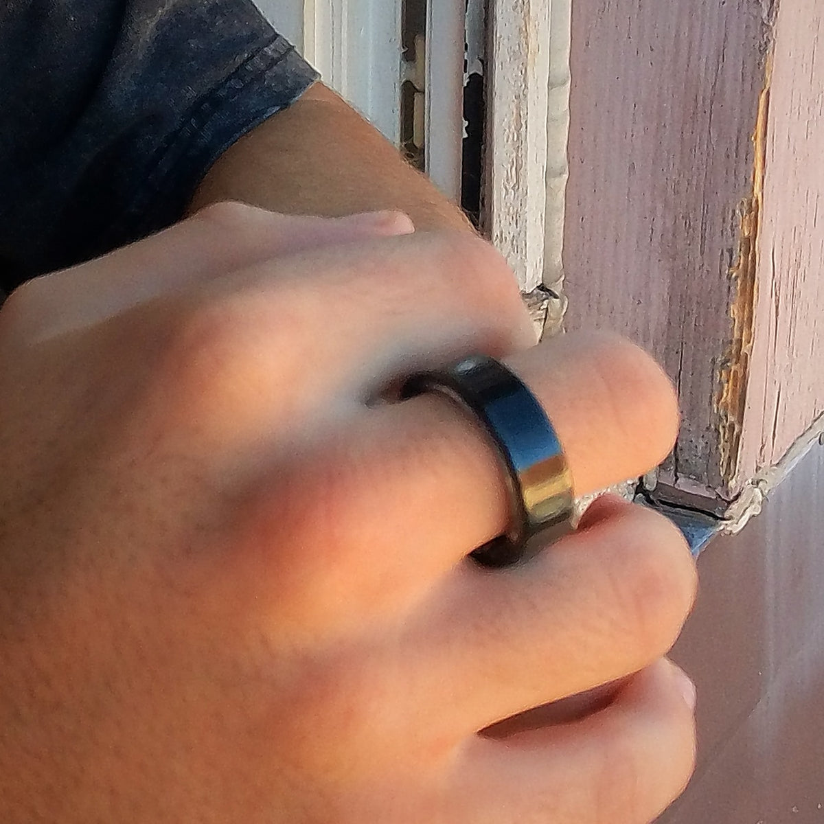 Bague connectée noire au doigt, main posée sur un rebord de fenêtre